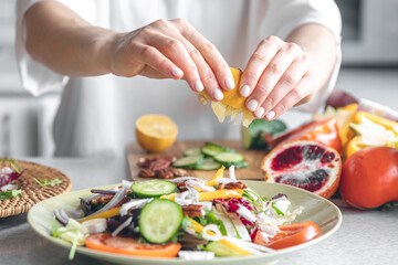 A woman makes a fresh vegetable salad, close-up.