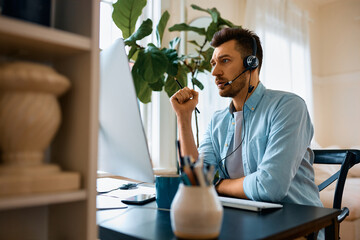 Mid adult businessman using computer while having video call from home office.