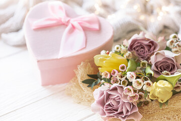 Spring composition with flowers and a gift box on a blurred background.
