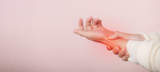 Young asian woman with white sweater cloth suffering from wrist hand pain injury. Causes of hurt include carpal tunnel syndrome, fractures, arthritis or trigger finger. world health day concept.