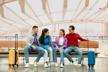 Obraz premium Two Happy Couples Tourists With Suitcases Sitting In Airport Indoors