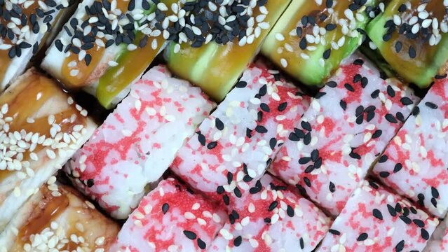 Set of colorful different kinds of sushi rolls placed on wooden board. Assortment of different kinds of sushi rolls on serving board