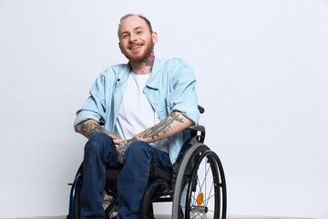 A man in a wheelchair and pointing a finger at, copy space, with tattoos on his hands sits on a...