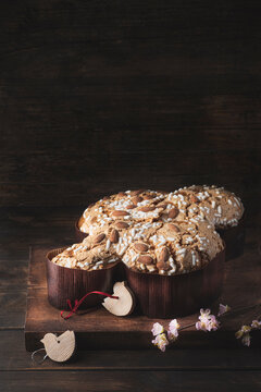 Сolomba pasquale - Italian sweet Easter bread or cake with almonds and powdered sugar and candied fruits. The baked dove is a symbol of Christ and the Easter holiday. Rustic wooden background