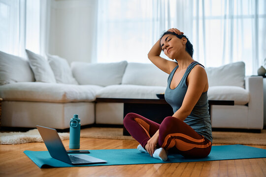 Sportswoman doing relaxation exercise while using laptop at home.