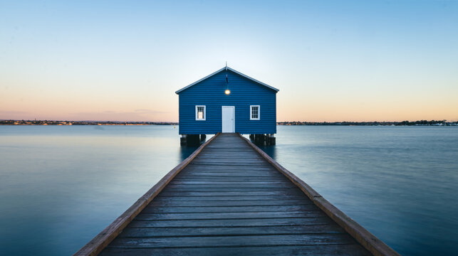 The beautiful blue boat house. The image was taken shortly after sundown. A long walk way leading the eye to the structure. An abundance of blues and a amber glow on the horizon. 