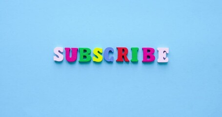 Text SUBSCRIBE from colorful wooden letters on a blue background. Looped 4K stop motion animation - Powered by Adobe