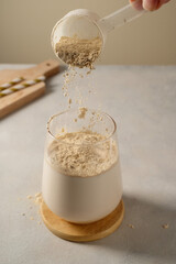 Pouring protein powder from scoop, in glass with milkshake.  - obrazy, fototapety, plakaty