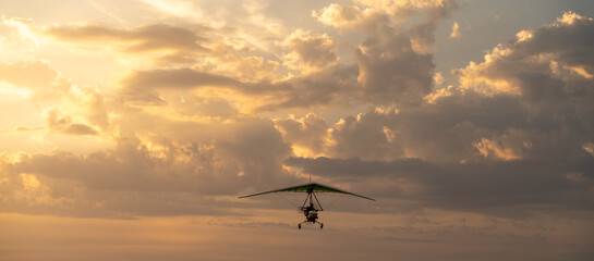 Propeller plane flies in the sunset sky. Banner, A small private hang-glider in a cloudy sky.