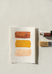 Minimalist flat lay with warm earthy color palette and painting tools, beige background with copy...