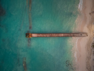 Top view of a wooden pier in the sea. White sandy beach. light turquoise sea water. Minimalism. Abstraction. There are no people in the photo. nature, ecology, recreation.