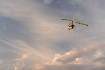 Propeller plane flies in the sunset sky. A small private hang-glider in a cloudy sky.