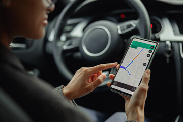 Closeup of female traveler using cell phone with gps navigation app on screen while sitting in car