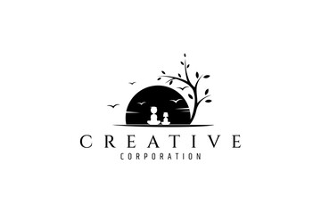 Vector logo design where a boy is sitting with his little sister in the shade of a beautiful tree overlooking the sunset with birds in the sky.