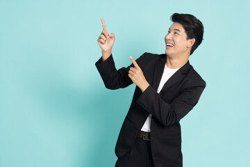 Young Asian businessman smiling and pointing to empty copy space isolated on green background