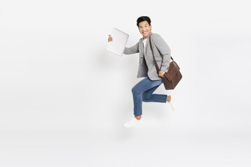 Young businessman jumping in air with laptop computer and brown leather bag isolated on white background, Full length composition - 580792407