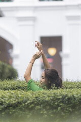 Asian model in green dress poses gracefully in city park, nature concept