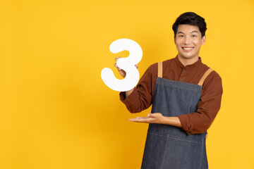 Restaurant owner sme young Asian man holding number 3 or three isolated on yellow background