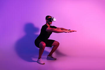 Fototapeta na wymiar Black Man Wearing VR Headset Exercising Doing Squats, Purple Background
