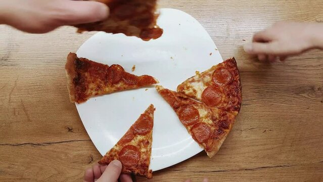 Top view human hands taking slices of pizza with cheese, tomatoes from food delivery.