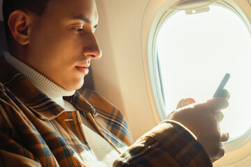 A man in an airplane looks at the phone, Wi-Fi in the airplane cabin. A tourist in a transport in...