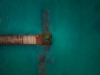 Shooting from a drone. Pier on the sea. Dark turquoise water and algae. Climate change, global warming, environmental protection, ecology.