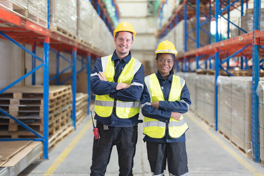 Two warehouse workers smile happily.