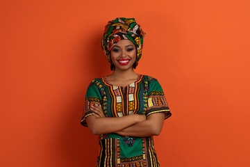 Cheerful african woman in traditional costume posing on orange