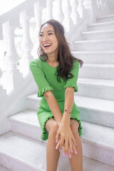 An elegant and beautiful Asian model in a green dress strikes a pose that's both graceful and captivating. Her dark hair, beautiful lips, and attractive facial features make for an alluring image 