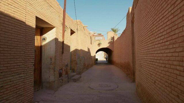 Narrow street in old medina with brick walls in Tunisia. Ancient constructions from Tozeur, North Africa. Holiday concept ideas.