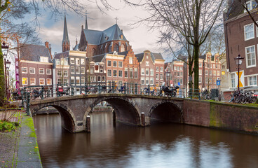 Naklejka premium Beautiful old houses on the city embankment of Amsterdam at sunset.