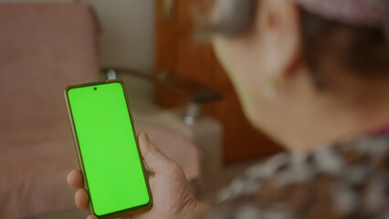 Connected and Tech-Savvy: Senior Woman Using Green-Screen Smartphone for Video Chat or App