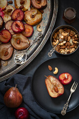 Baked apples, pears and plums with almonds, nuts and honey. Vintage tableware. Delicious and healthy dessert. Top view.  Low key photography.