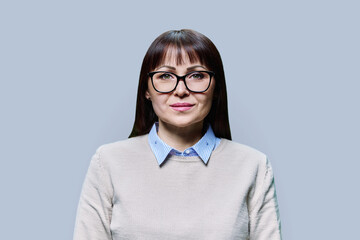 Headshot portrait of middle aged woman looking at camera on light background