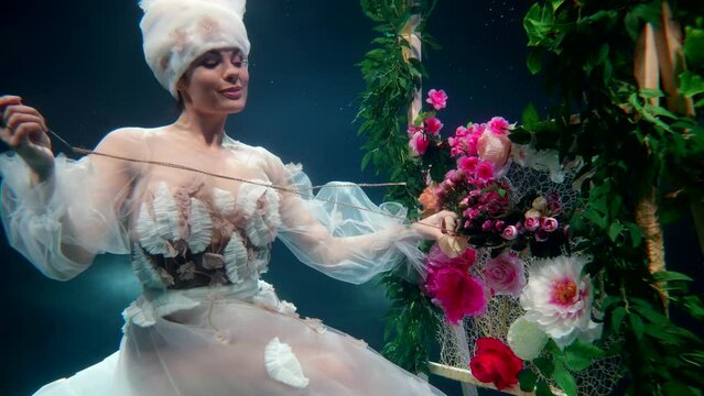 an elegant fairy-tale lady craftswoman under water like a mermaid knits a rug with threads