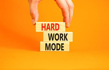 Hard work mode symbol. Concept words Hard work mode on wooden block on a beautiful orange table...
