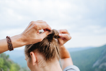 The guy collects his hair in a bun with his hands, the man ties a pigtail on his head, long male hair from behind, the back of the head, make a knot with his hands.