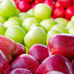 Fresh red and green apples spread on the counter for sale, create a natural, colorful background.