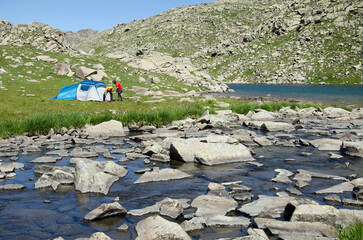 Two hikers mountaineers pitch a tent on the ground near the lake. Kaçkar Mountains National Park, Turkey