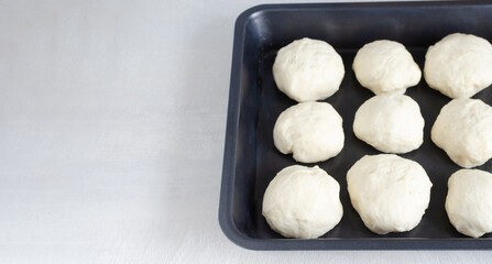 Future buns in baking form. Preparation of pampushky (Pampushky), traditional Ukrainian buns for borsch. The concept of traditional dishes. Homemade baking. Horizontal orientation. Copy space