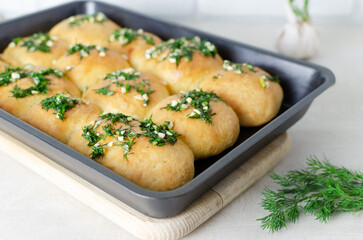 Buns with garlic and dill sauce with oil in a baking dish. Preparation of pampushky (Pampushky), traditional Ukrainian buns for borsch. The concept of traditional dishes. Homemade baking.