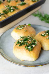 Three buns with garlic and dill sauce with oil in a gray plate. Preparation of pampushky (Pampushky), traditional Ukrainian buns for borsch. The concept of traditional dishes. Homemade baking.