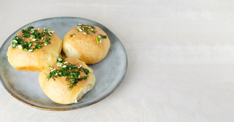 Three buns with garlic and dill sauce with oil in a gray plate. Preparation of pampushky (Pampushky), traditional Ukrainian buns for borsch. The concept of traditional dishes. Copy space