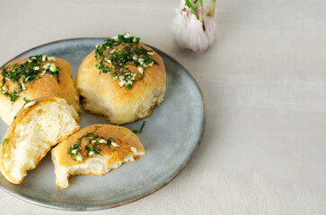 Three buns with garlic and dill sauce with oil in a gray plate. Preparation of pampushky (Pampushky), traditional Ukrainian buns for borscht. The concept of traditional dishes. Homemade baking.