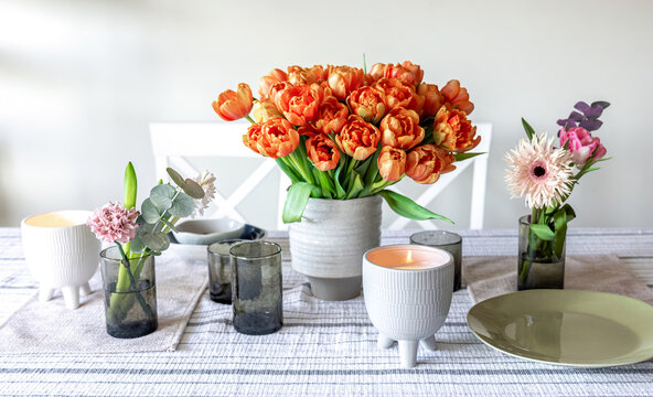 Spring flowers and candles on the table in the interior of the room.
