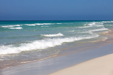 Ocean beach with white sand, view to azure waves and clear sky. Background for holidays on a paradise nature