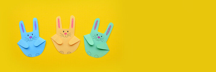 Banner. Easter craft from the imprint of a child's palm. Easter bunnies made of colored paper on a yellow background