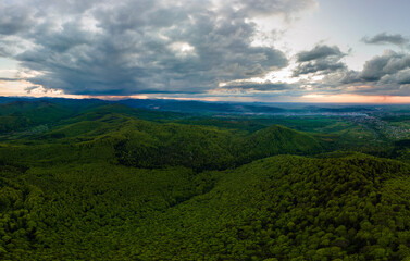 Fototapeta na wymiar Aerial view of dark mountain hills covered with green mixed pine and lush forest in evening