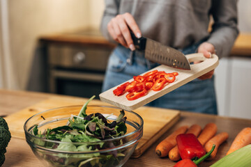 Adding chopped red peppers to the salad