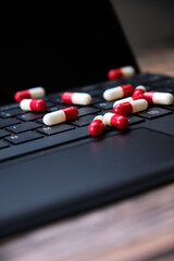 Close-up of a pile of white and red capsules on top of a computer keyboard.